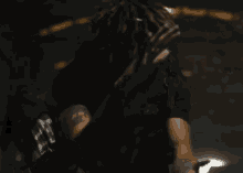 a man with dreadlocks is sitting in a dark room holding his hands together .