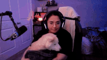 a woman is sitting in a chair holding a puppy in her lap .