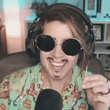 a woman wearing sunglasses and headphones is smiling and holding a toothpick in front of a microphone