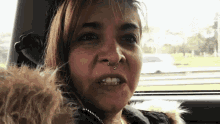 a woman is sitting in a car with a dog and making a funny face .