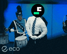 a man in a blue marching band uniform is playing drums in front of a sign that says eco