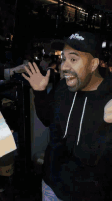 a man wearing a black sweatshirt and a black hat is clapping
