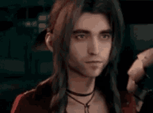 a man with long hair is wearing a choker and a red jacket .