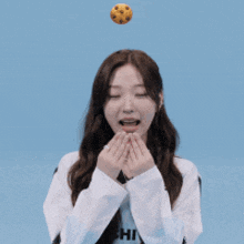 a girl with her eyes closed and a cookie flying in the air