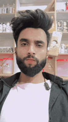 a man with a beard is wearing ear buds and a white shirt