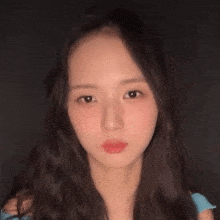 a close up of a woman 's face with long hair and a blue shirt .