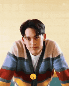 a young man wearing a striped sweater has a yellow smiley face on his chest