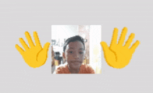 a boy 's face is behind a pair of yellow emoji hands