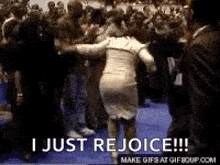 a woman is dancing in front of a crowd with the words `` i just rejoice '' above her .