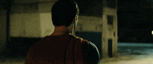 a man in a superman costume stands in front of a building at night