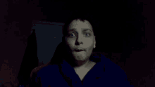 a young man with blue eyes is making a face in the dark