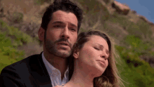 a man in a suit and a woman in a dress are standing next to each other on a beach .
