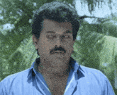 a man with a mustache is wearing a blue shirt and looking down