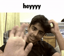 a young man is waving his hand in front of a sign that says heyyyy