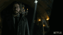 a man in a suit and tie stands in a dark room with a netflix logo on the bottom right
