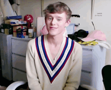 a young man wearing a sweater with a v-neck is smiling