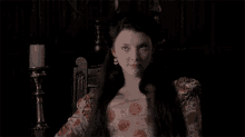 a woman in a red and white dress is sitting in a chair