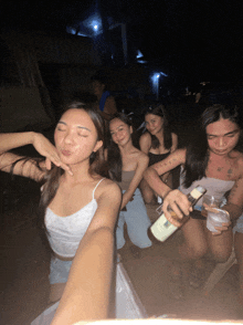 a group of young women are posing for a picture with one holding a bottle
