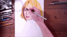 a person is drawing a woman 's face on a piece of paper with a marker that says uniball on it
