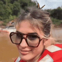 a woman wearing sunglasses and a life jacket smiles at the camera