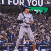 a baseball player in a new york jersey is holding a bat in front of a crowd at a baseball game .