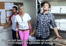 a man and a woman are standing in front of a bulletin board talking about scooby doo .