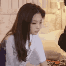 a woman with long hair is sitting on a bed with a tablet in her hand .