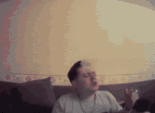 a man is sitting on a couch with his eyes closed and a bottle in his hand