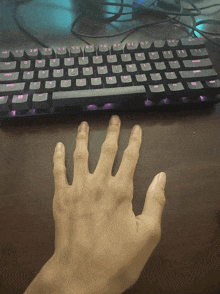 a person 's hand is reaching out towards a keyboard with the shift key highlighted in pink