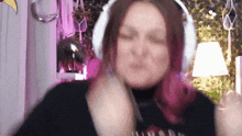 a woman with pink hair wearing headphones is making a funny face .