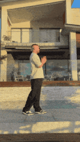 a man standing in front of a large house with his hands together