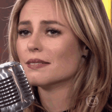 a close up of a woman 's face with a silver microphone in front of her