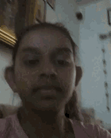 a girl is covering her mouth with her hand in front of a picture on the wall