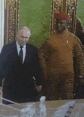 a man in a suit and tie is talking to a man in a military uniform with the word army on his shirt