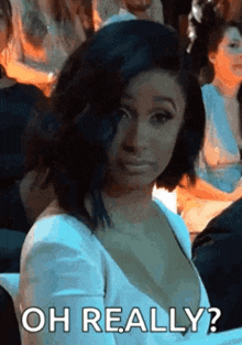 a woman in a white dress is sitting in a crowd .