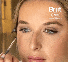 a woman is getting her makeup done in front of an advertisement for brut