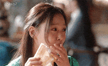 a close up of a woman eating a sandwich .