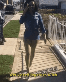 a woman walking down a sidewalk with the words get yo ' self together bitch written above her