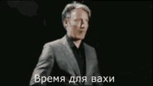 a man in a suit is looking at his watch with the words " время для васи " written below him