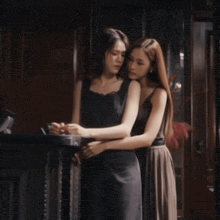 two women standing next to each other with one wearing a black tank top