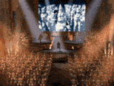 a large group of people are gathered on a stage with a large screen behind them
