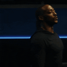 a man in a black shirt stands in the dark with his eyes closed