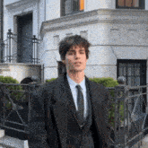 a man in a suit and tie is standing in front of a building with the letter e on it