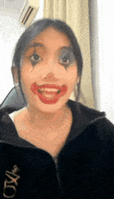 a woman is wearing clown makeup and a black jacket .
