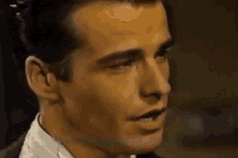 a close up of a man 's face in a suit and tie talking on a cell phone .