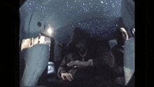 a man in a hoodie is sitting in the back seat of a car with a starry ceiling .