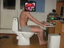 a shirtless man sits on a toilet with a picture of a cat on his face