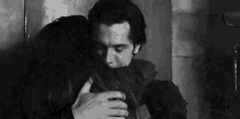 a black and white photo of a man hugging a woman .