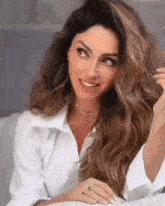 a woman in a white shirt is sitting at a table with her hair in her hand .