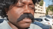 a man with a mustache and a wig is making a funny face .